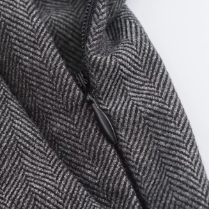 Macro detail of dark grey herringbone fabric texture and invisible black zipper closure