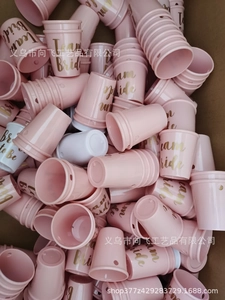Pink and white Team Bride shot glasses with beaded chains stacked in a bulk box