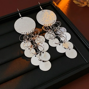 Macro detail of silver sequin tassel earrings on a premium black leather jewelry box