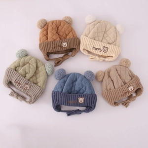 Detail von fünf Strickmützen für Babys in Morandi-Farben mit Bären-Patches und Pompons
