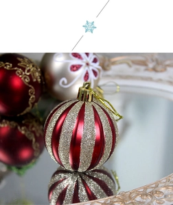 Close-up of red and gold striped Christmas bauble with glitter and mirror reflection