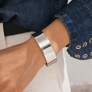 Close-up of a wide minimalist silver bangle with a polished mirror finish on a woman's wrist