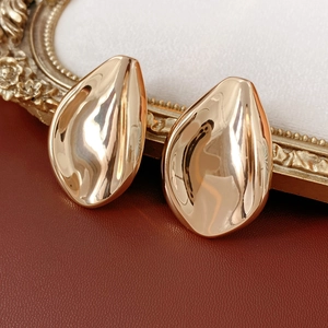 Close-up of golden teardrop earrings with a glossy metallic finish on a vintage frame