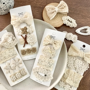 Set of 4 beige lace and fabric bow hair clips for girls on a wooden background