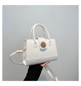 Détail du sac à main blanc structuré avec relief crocodile et fermoir floral doré chic