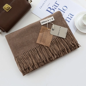 Brown cashmere-feel scarf with tassels and label, styled on white table with accessories