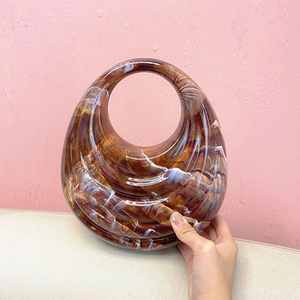 Detail of brown marble acrylic handbag with unique oval shape and integrated round handle