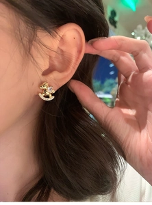 Detailed close-up of a model wearing a gold rocking horse stud earring with sparkling zircon