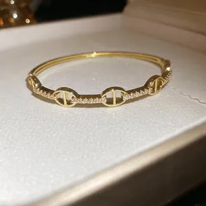 Elegant gold plated oval bangle featuring sparkling zircon stones and chain link design