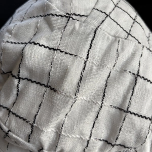 Detailed macro view of white linen plaid fabric with intricate black stitching texture
