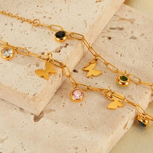 Detail of gold butterfly necklace with colorful zircon stones on textured stone
