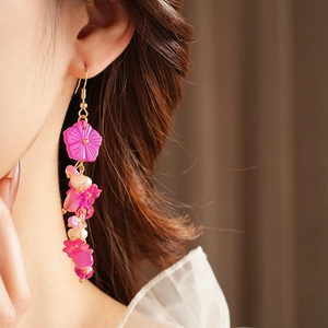 Gros plan de boucles d'oreilles pendantes avec perles et fleurs roses sur un mannequin