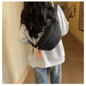 Rear view of model wearing a black nylon crescent sling bag with orange drawstrings