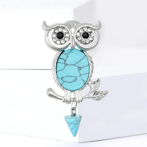 Vintage silver owl brooch with turquoise stone and crystal accents on white background