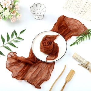 Detail of bohemian brown cheesecloth table runner with soft crinkled texture and flower fold
