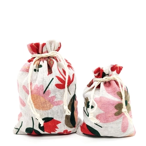 Detail view of cotton drawstring gift bags with red floral pattern on white background