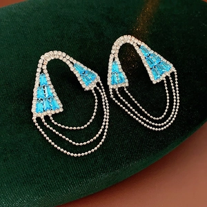 Dettaglio di orecchini geometrici in argento con nappe di cristallo azzurro