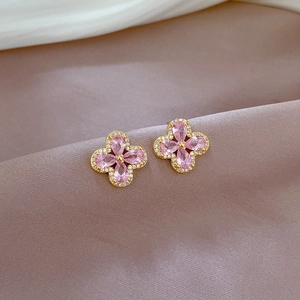Detail of clover earrings with pink teardrop stones and gold finish on purple silk fabric