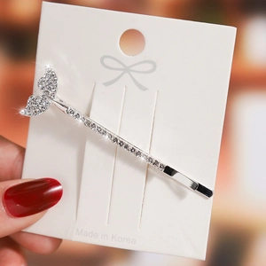Close-up of a silver mermaid tail hair clip with sparkling rhinestones on a card