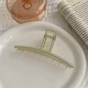 Close-up of textured silver metal shark hair claw clip on a stylish decorative setting