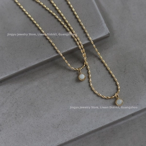 Macro shot of 18K gold plated rice chain necklace with dual round white stone pendants