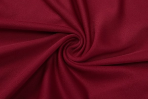 Macro detail of wine red knitted polyester fabric showing texture and fold patterns