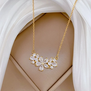 Detail of luxury gold zircon flower pendant on a textured leather and silk background