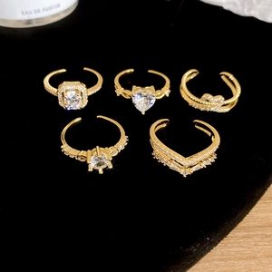 Close-up of five adjustable gold-plated zircon rings on black velvet display stand