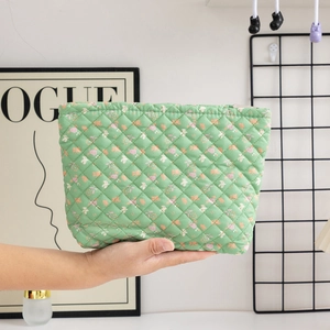 Detail of hand holding floral quilted cotton makeup bag with green and pink patterns