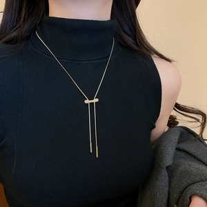 Gros plan d'un collier en Y doré avec curseur en zircon sur un pull en cachemire noir