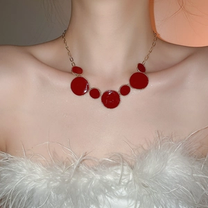 Détail d'un collier vintage avec des pendentifs circulaires en émail rouge et chaîne dorée