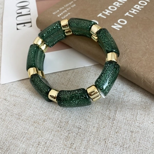 Detail of beaded bracelet featuring dark green glitter resin and polished gold spacers