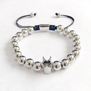 Detail of silver crown bead bracelet featuring black braided rope and metallic beads