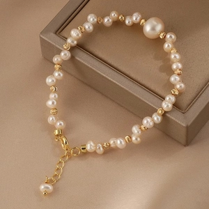 Dettaglio macro dell'elegante bracciale di perle d'acqua dolce e grani dorati su velluto