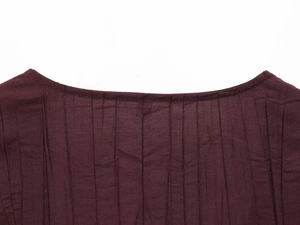 Macro detail of the deep purple pleated fabric texture and neckline on the sleeveless top