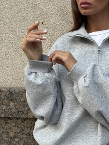 Close-up of grey half-zip sweatshirt showing ribbed cuffs and premium knit texture