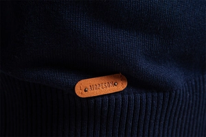 Detailed close-up of navy blue knit sweater texture and embossed leather hem label
