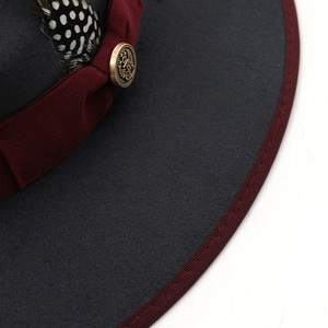Close-up of wool felt jazz hat with burgundy ribbon, vintage buckle and guinea feather