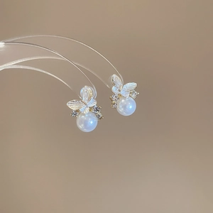 Detail of gold butterfly earrings with white pearls and sparkling diamond accents
