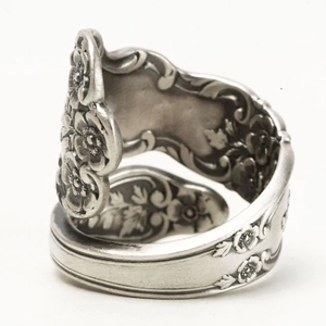 Detail showing vintage silver spoon ring with intricate embossed flower and leaf patterns