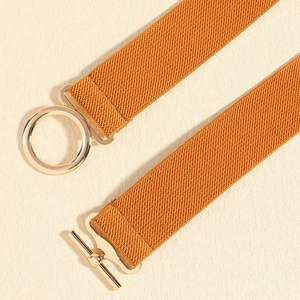 Detailed close-up of orange elastic waist belt with round gold buckle and T-bar fastener