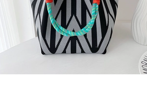 Detailed view of black and white geometric knit handbag with colorful braided rope handles