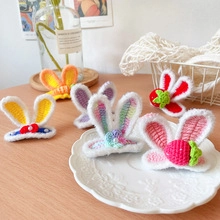 Close-up of handmade crochet rabbit ear hair clips with strawberry and floral details