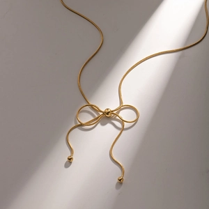 Elegant gold snake chain necklace featuring a butterfly knot design with beads