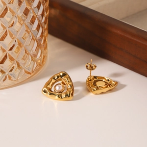 Textured triangle stainless steel stud earrings with central pearl on warm background
