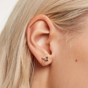 Detail view of gold stud earring with colorful gems and delicate chain on model