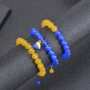 Close-up of three yellow and blue beaded bracelets with a heart pendant on a display