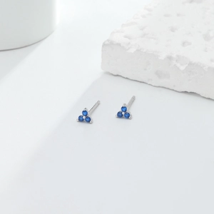 Detail of S925 sterling silver triangle studs with blue stones on a white background