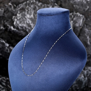 Detailed view of shimmering silver box chain necklace on a blue velvet neck bust display
