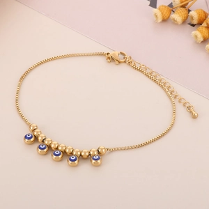 Detail of 18K gold plated anklet featuring blue evil eye charms and small gold beads